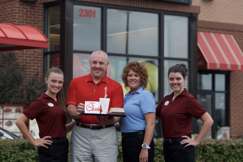 Oscar Fittipaldi family photo with his wife and grown kids outside of Chick-fil-A.