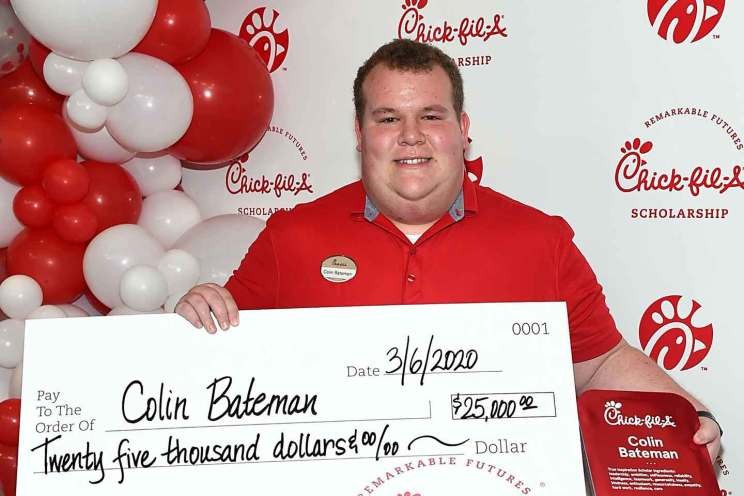 Colin Bateman holds a large $25,000 Chick-fil-A scholarship check and award plaque while smiling in front of a branded balloon backdrop.