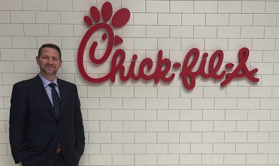 Kurt Milne smiling standing next to a Chick-fil-A sign.
