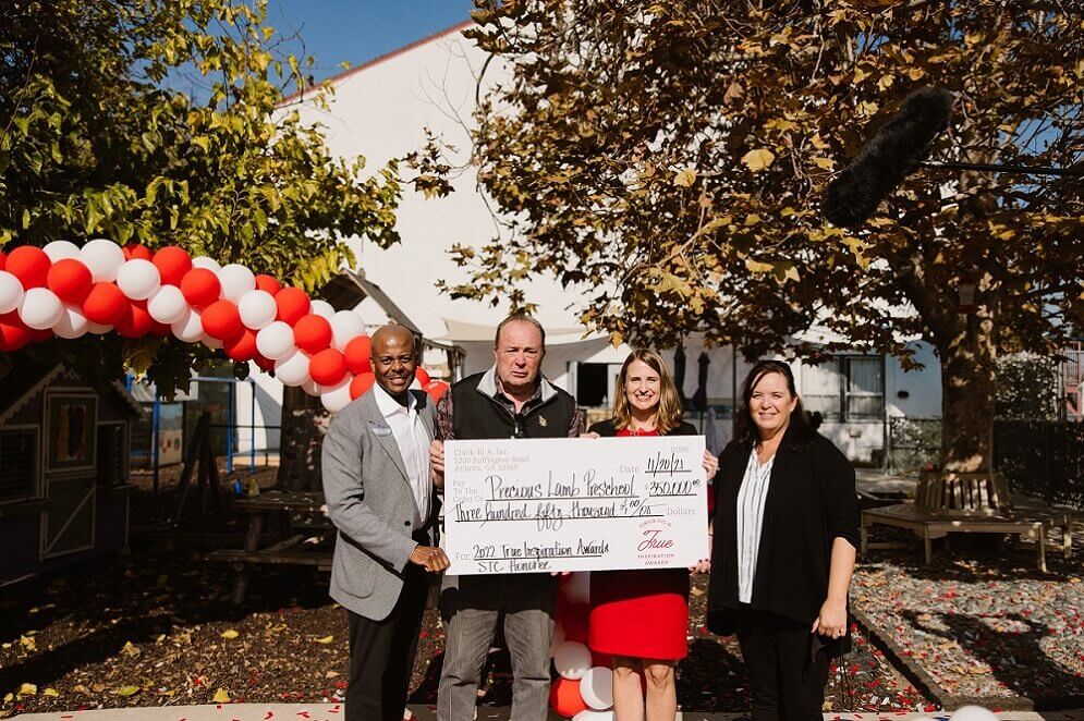 A group of four people hold a large check.