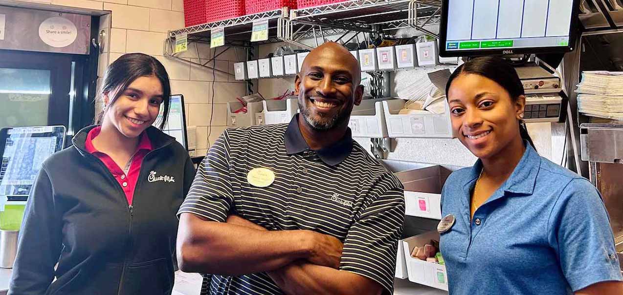 Marlon Terrell and two team members in the Chick-fil-A drive-thru area inside the restaurant.