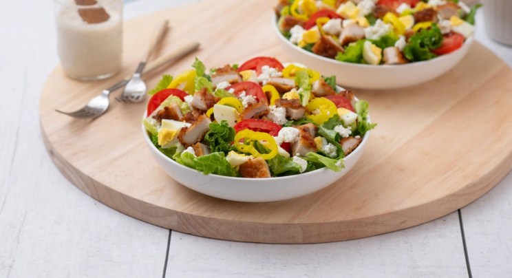 A tray with two garden salads topped with chicken