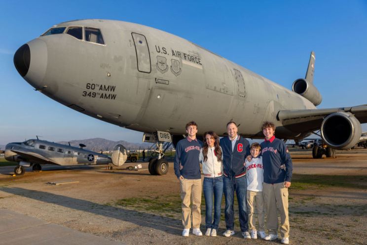 US Air Force Veteran Eric Jeppsen with his family with a U.S. Air Force plane in the background.