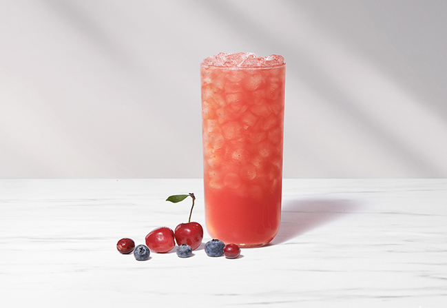 A glass of Cherry Berry Sunjoy with cherries and assorted berries next to the glass.