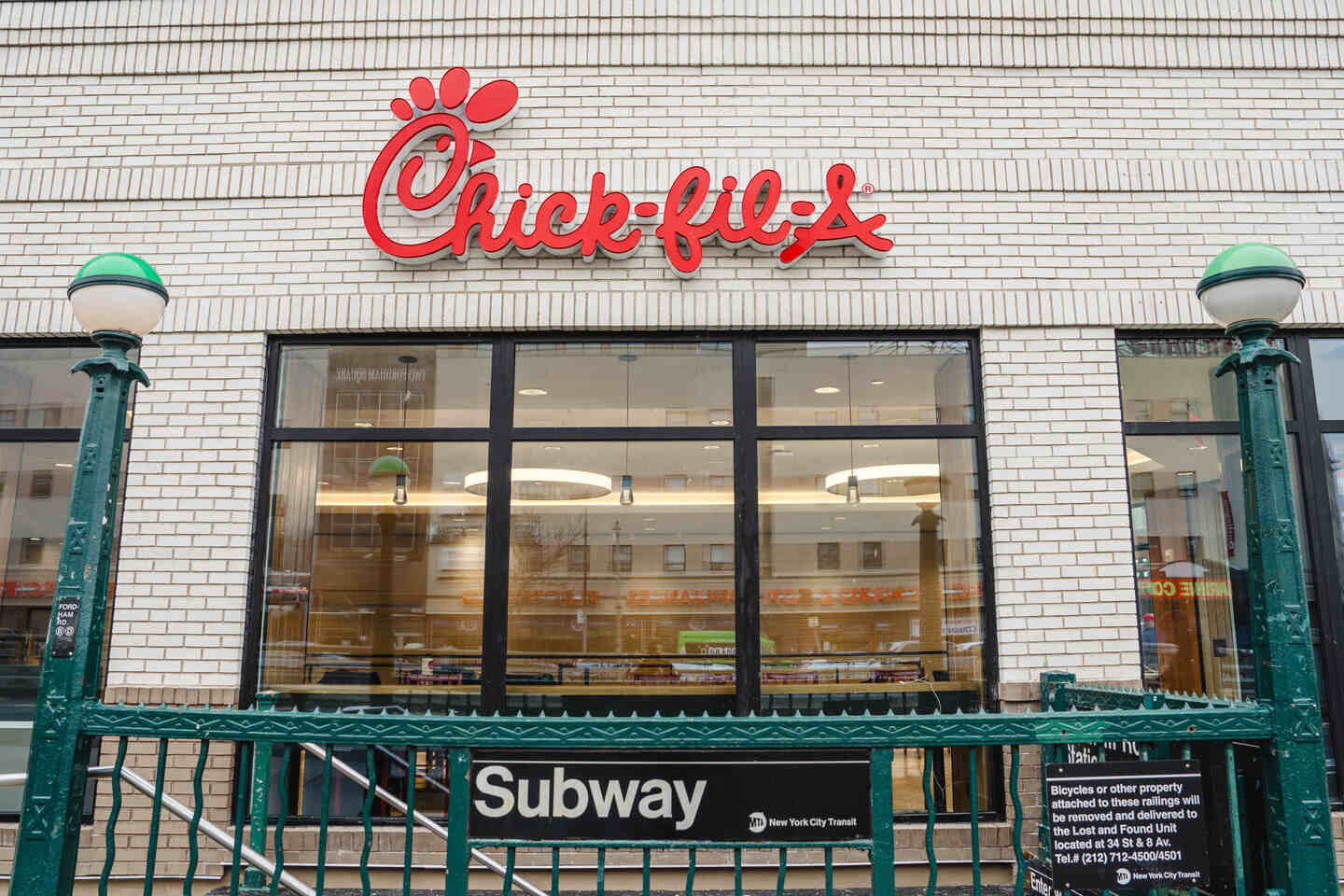 Exterior of Chick-fil-A with prominent red logo above a New York City subway entrance.