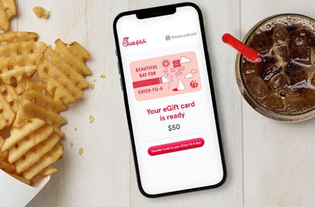 A smartphone on a table displaying an eGift card notification, next to waffle fries and a glass of soda.