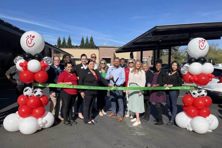 A group of people standing outside of a Chick-fil-A Microgrid Pilot Location and cutting a large ribbon
