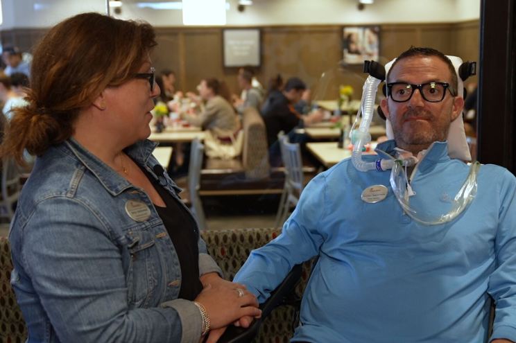 Two people sitting in a Chick-fil-A restaurant, with one person wearing a blue shirt and a medical device.