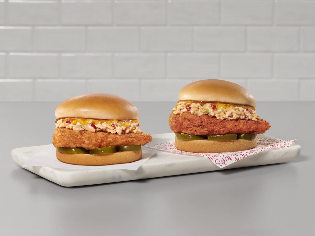Two Honey Pepper Pimento Chicken Sandwiches on a serving board. One is spicy and one is original.