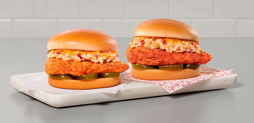 Two Honey Pepper Pimento Chicken Sandwiches on a serving board. One is spicy and one is original.
