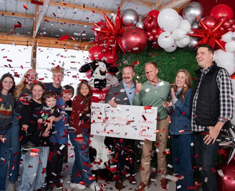 A group of people celebrating with confetti and balloons, one holding a large check.