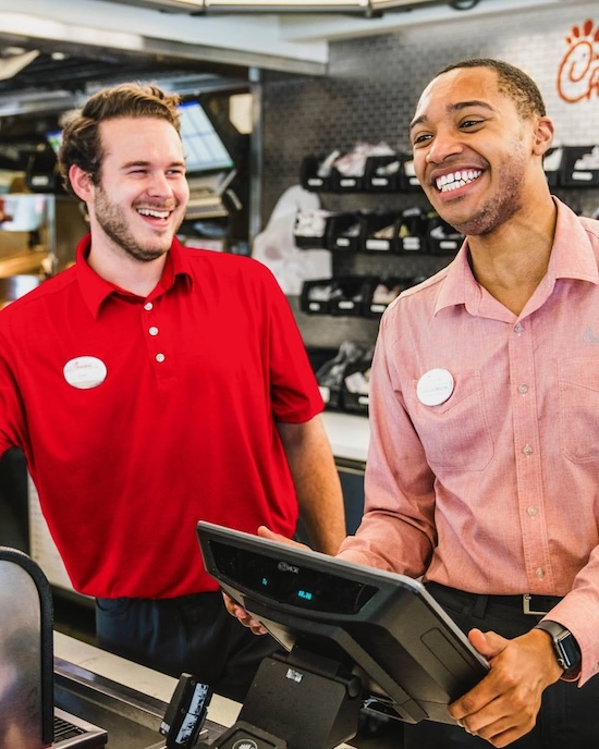 Two team members smiling at the register.