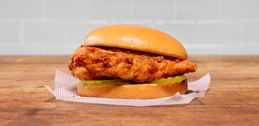 Original Chick-fil-A® Chicken Sandwichresting on a square piece of white paper that has a subtle red dotted pattern.