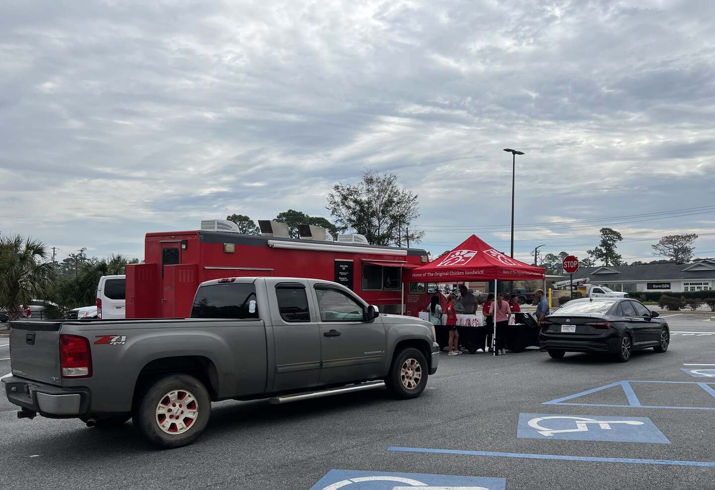 Chick-fil-A team members prepare and distribute meals under a red tent in a parking lot for hurricane relief.
