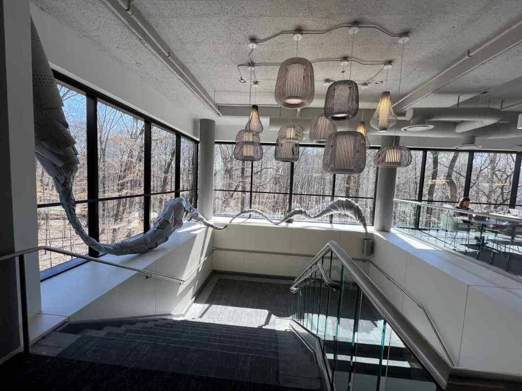 Interior with modern staircase, pendant lights, large windows, and art installation.