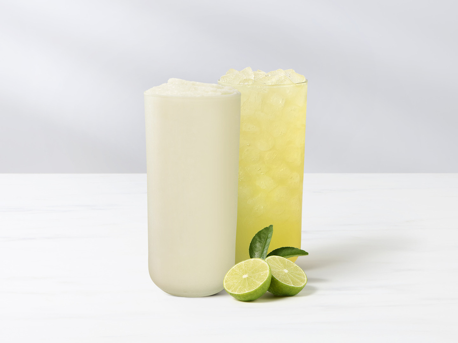 A glass of Key Lime Lemonade and a glass of frozen Key Lime Lemonade with a sliced fresh key lime.