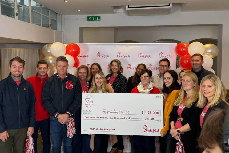 A group of people with an oversized check made out to to Hospitality Action.