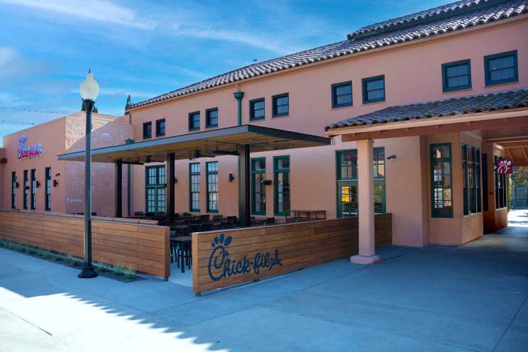 Chick-fil-A restaurant with stucco walls, a clay tile roof, and a covered outdoor seating area.