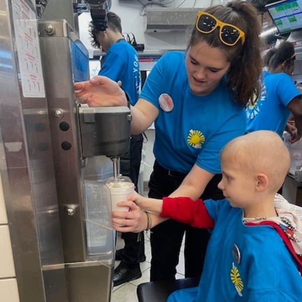 A little boy makes a shake with the help of Chick-fil-A team member