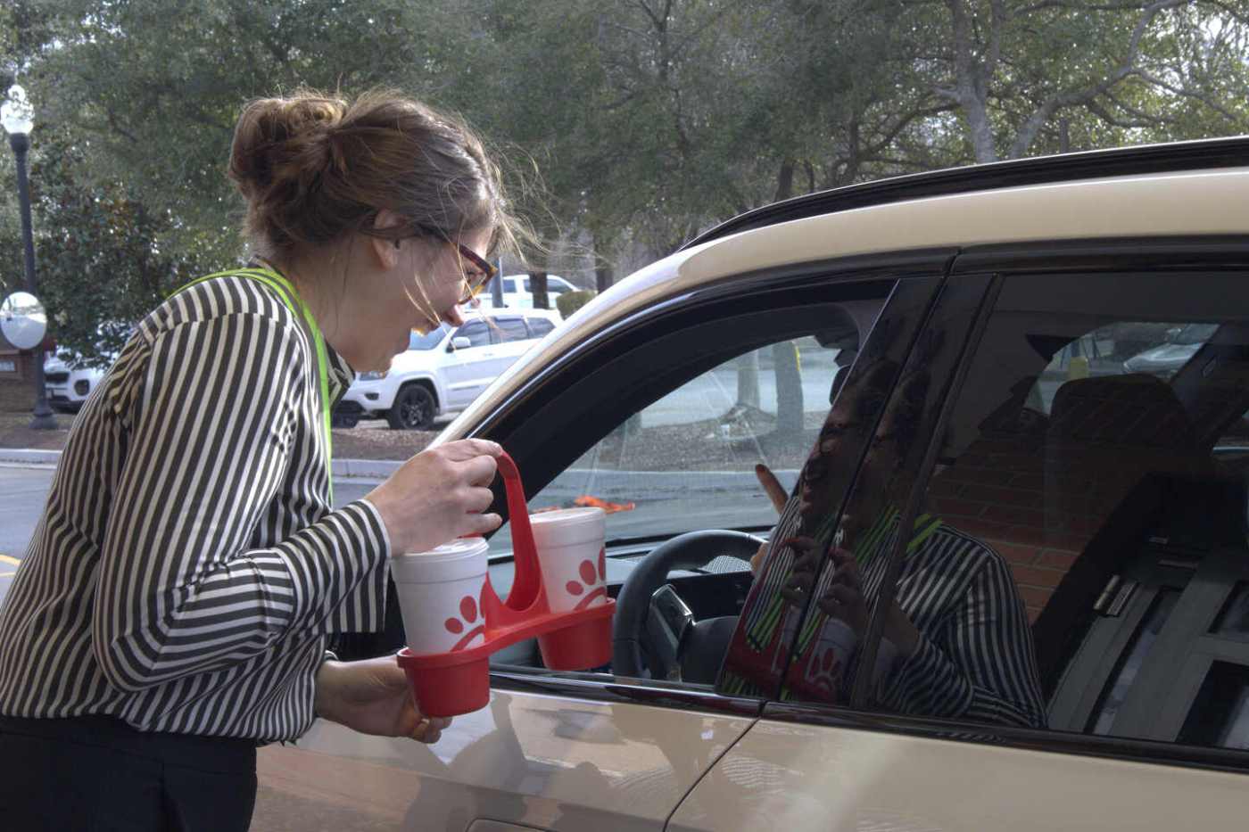 Chick-fil-A team member handing a drive-thru customer a reusable caddy.