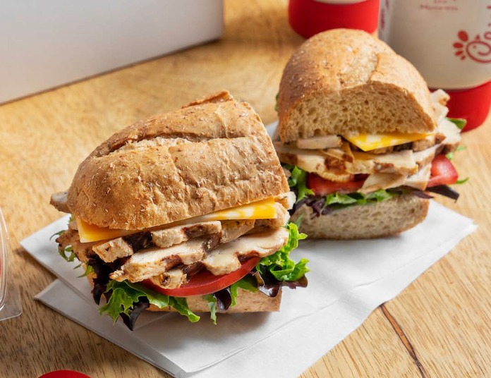 Two grilled chicken sandwiches with lettuce, tomato, and cheese on whole-grain buns.
