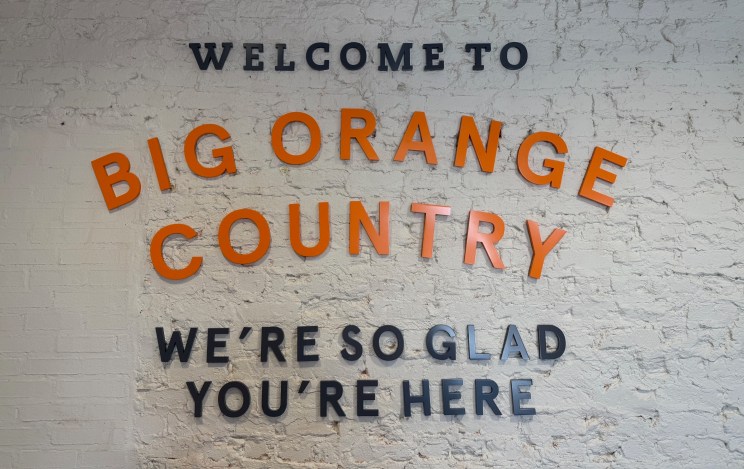 Text on a brick wall reads, "WELCOME TO BIG ORANGE COUNTRY. WE’RE SO GLAD YOU’RE HERE."