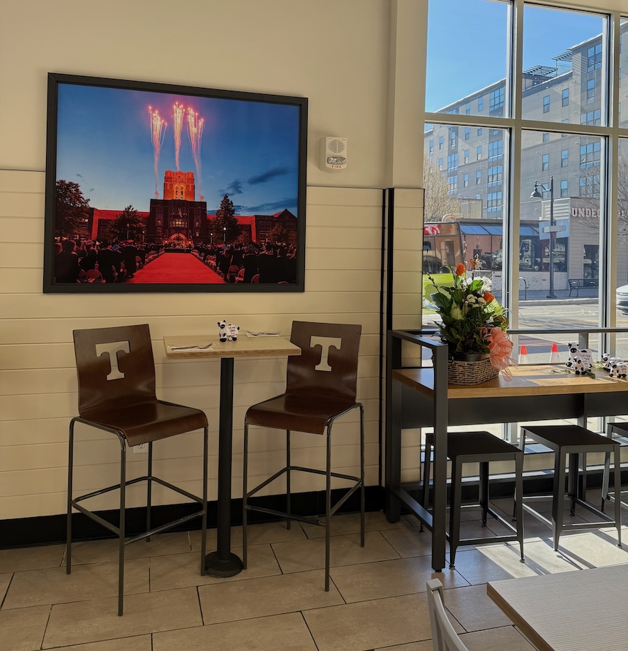 Interior of restaurant with high chairs and a framed photograph on the wall.