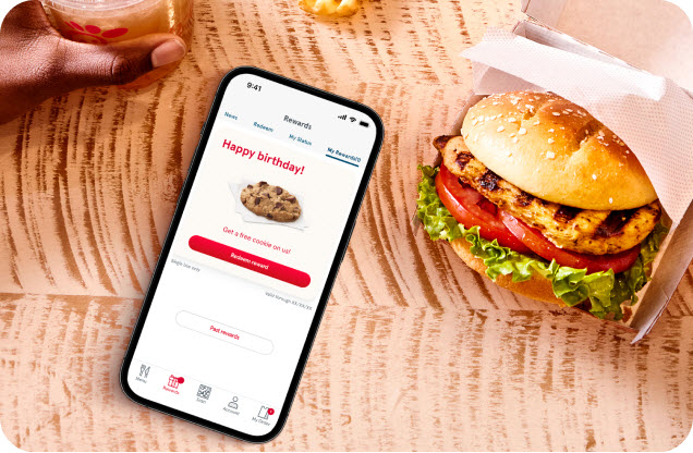 Smartphone on a table showing the Chick-fil-A app with the words Happy birthday on the screen