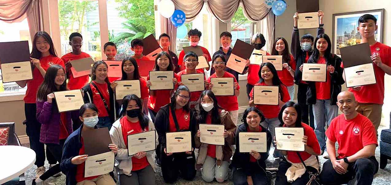 A group of middle-schoolers smiling, holding certificates.