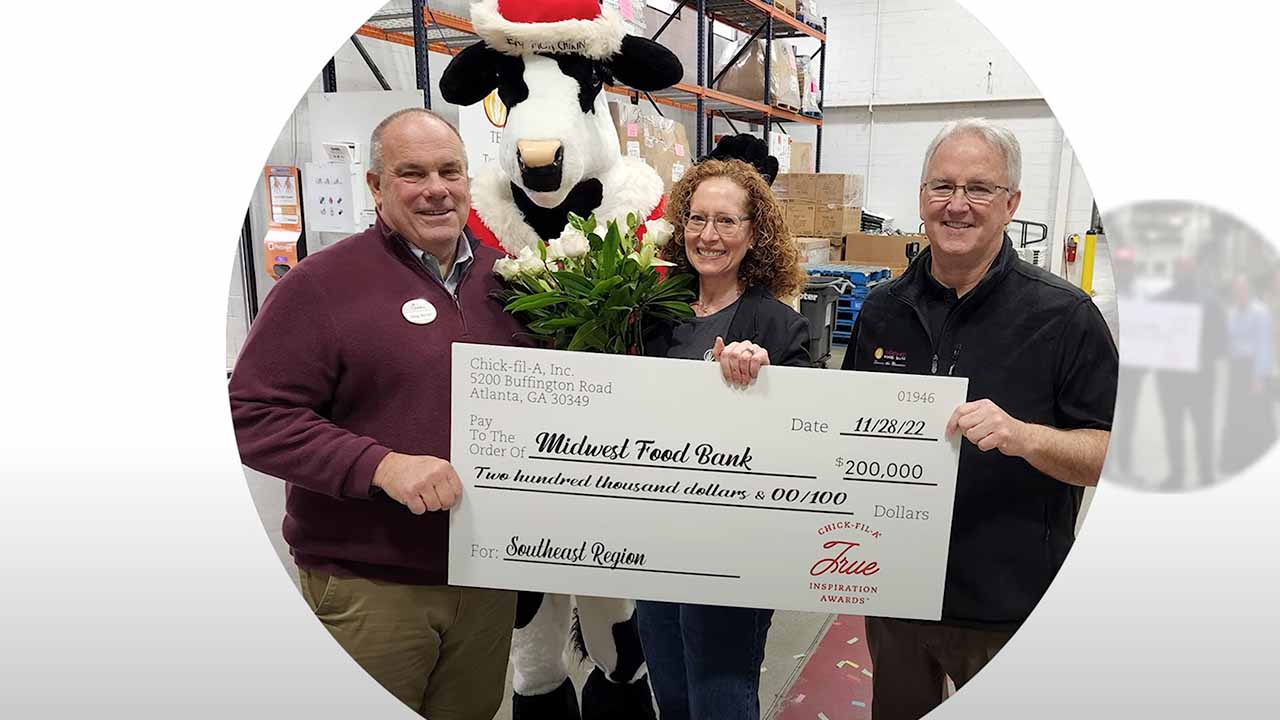 A group of three people hold a large check.