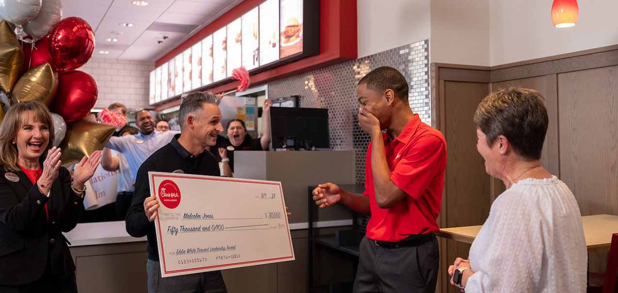Eddie White recieves a large Chick-fil-A scholarship check while others cheer in the background.