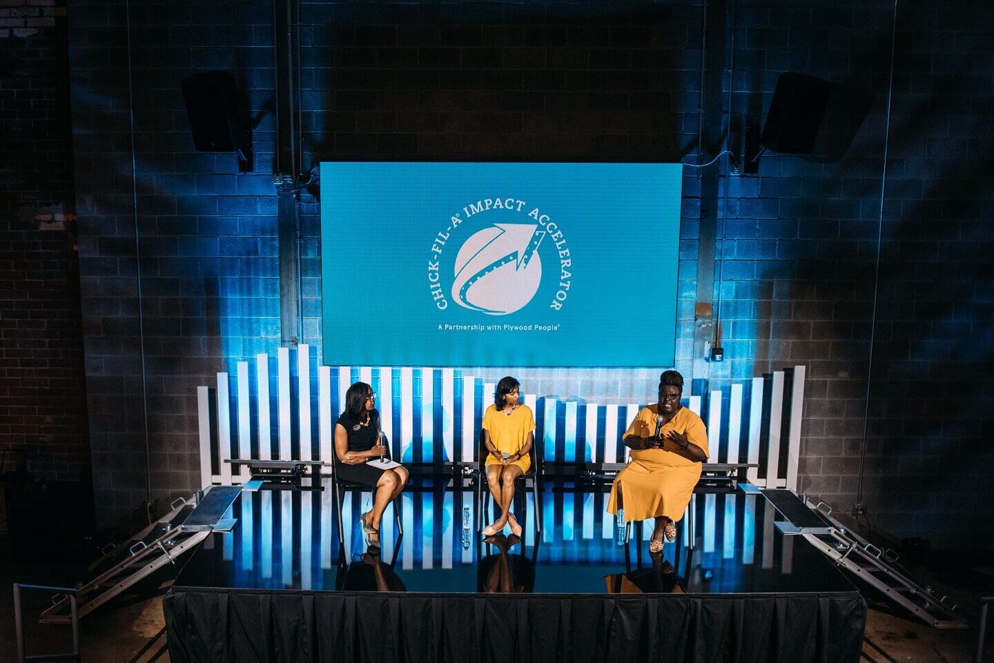 Three woman on stage in a panel at a conference.