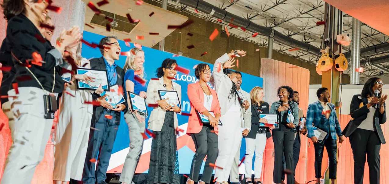 A group of people on stage celebrating as confetti falls down.
