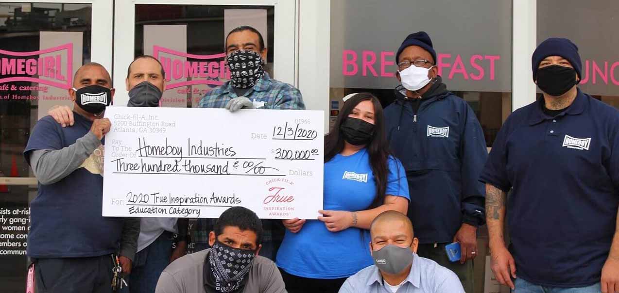 A group of people with an oversized check made out to Homeboy Industries.