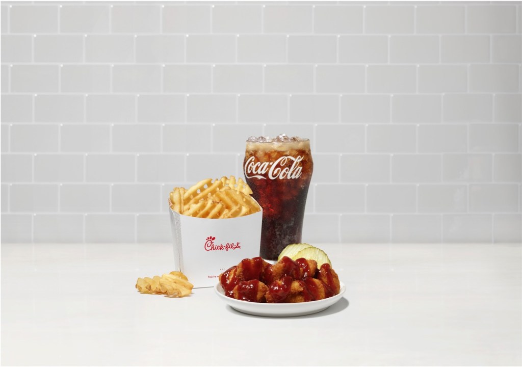 A plate of Smokehouse BBQ Nuggets and with Waffle Fries and a Coca-Cola on a white countertop with a gray tiled background