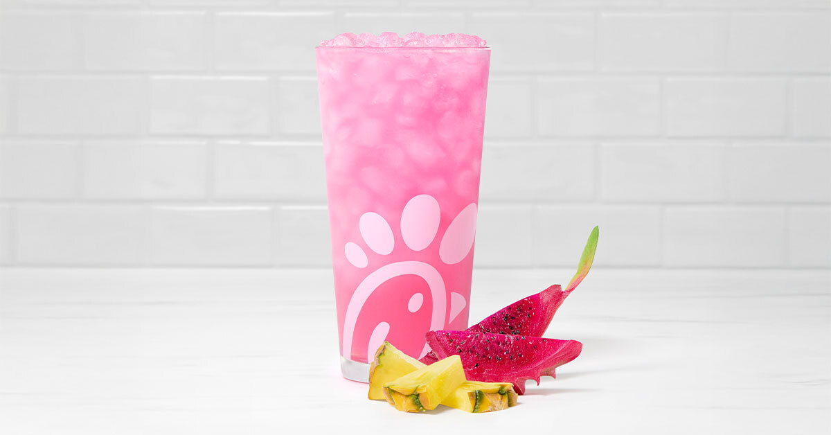 A glass of a Pineapple Dragonfruit Lemonade accompanied by slices of pineapple and dragon fruit.