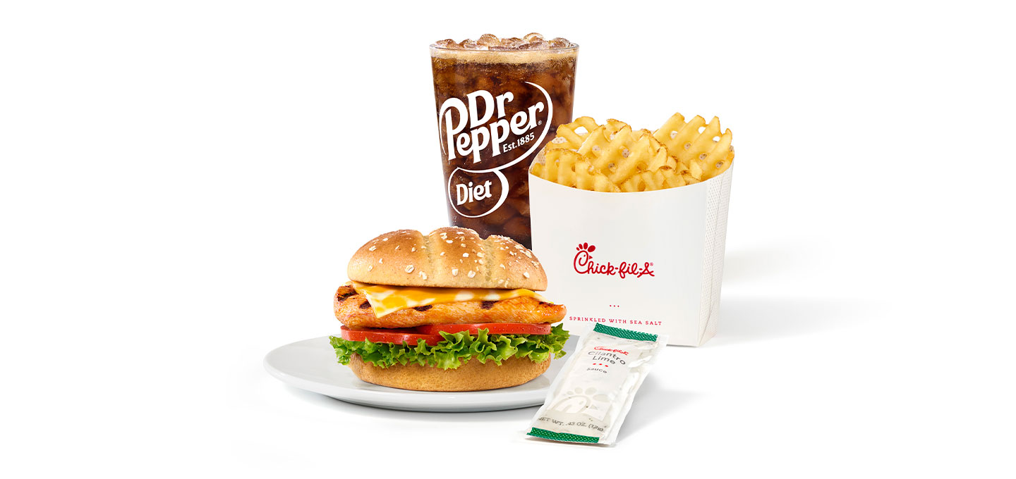 Grilled Spicy Deluxe on a plate served as a meal with Cilantro Lime Sauce waffle fries and a soft drink on a white background.
