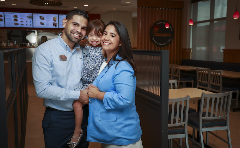 Questell Pereira with his wife and daughter inside of his restaurant.
