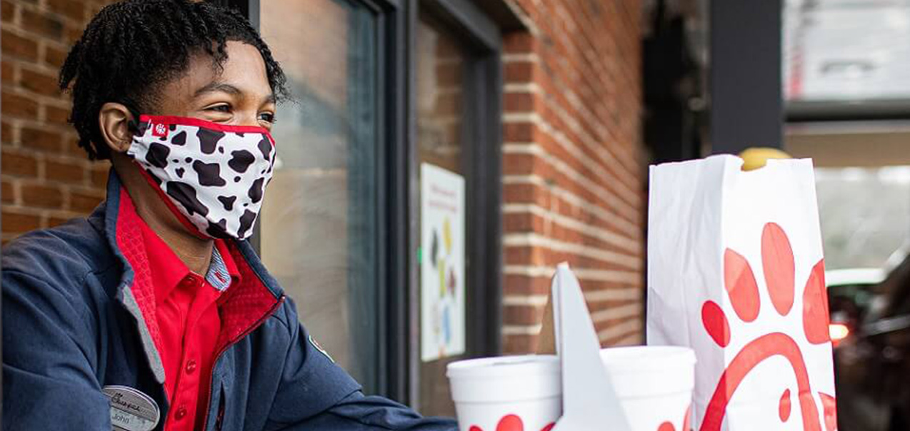 A Chick-fil-A team member hands food to a customer in the drive-thru