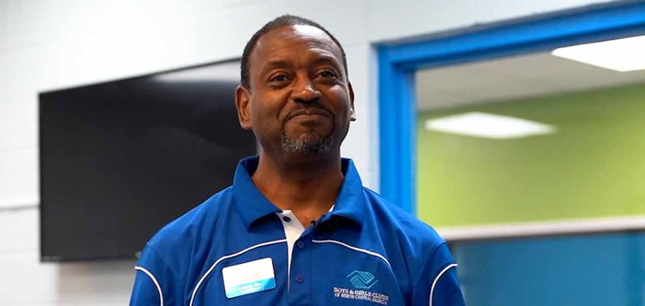 A man smiling wearing a Walton County Boys & Girls Club shirt.