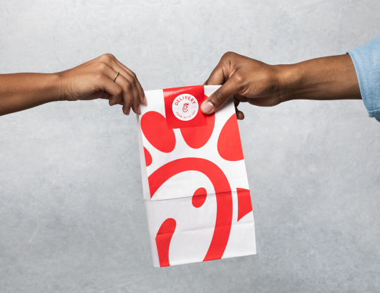 A team member handing a Chick-fil-A bag to a customer.