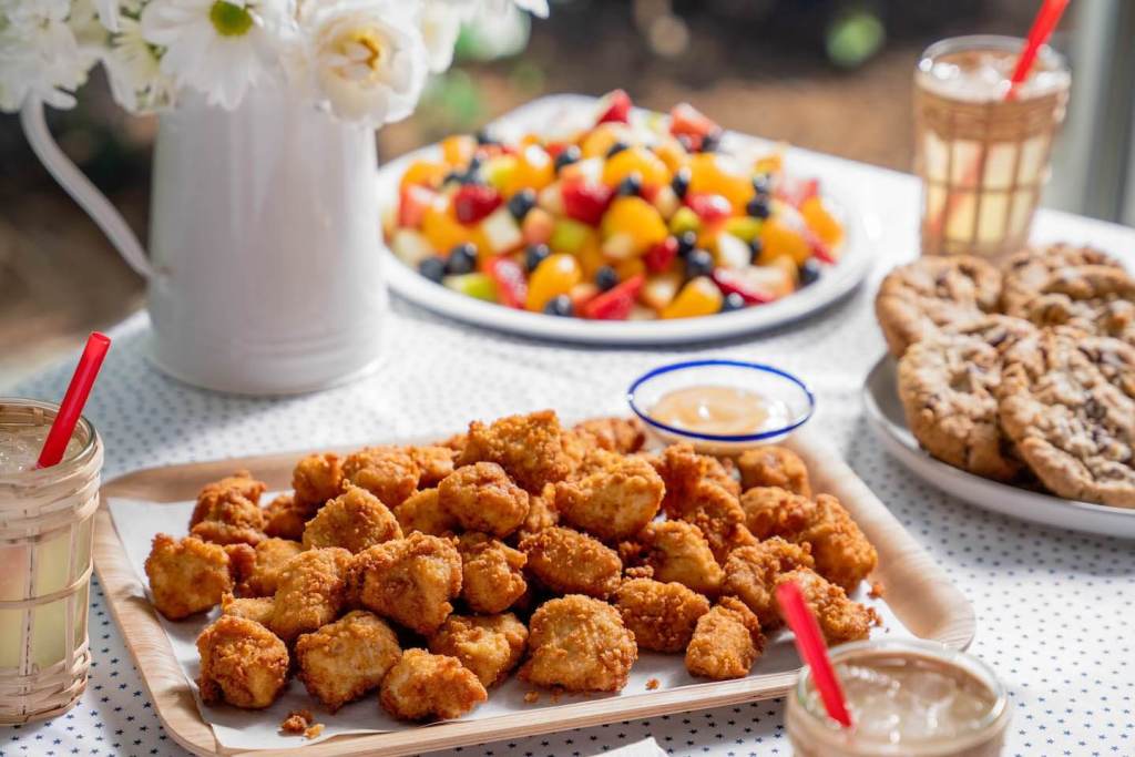 Catering trays including nuggets, cookies and fruit.