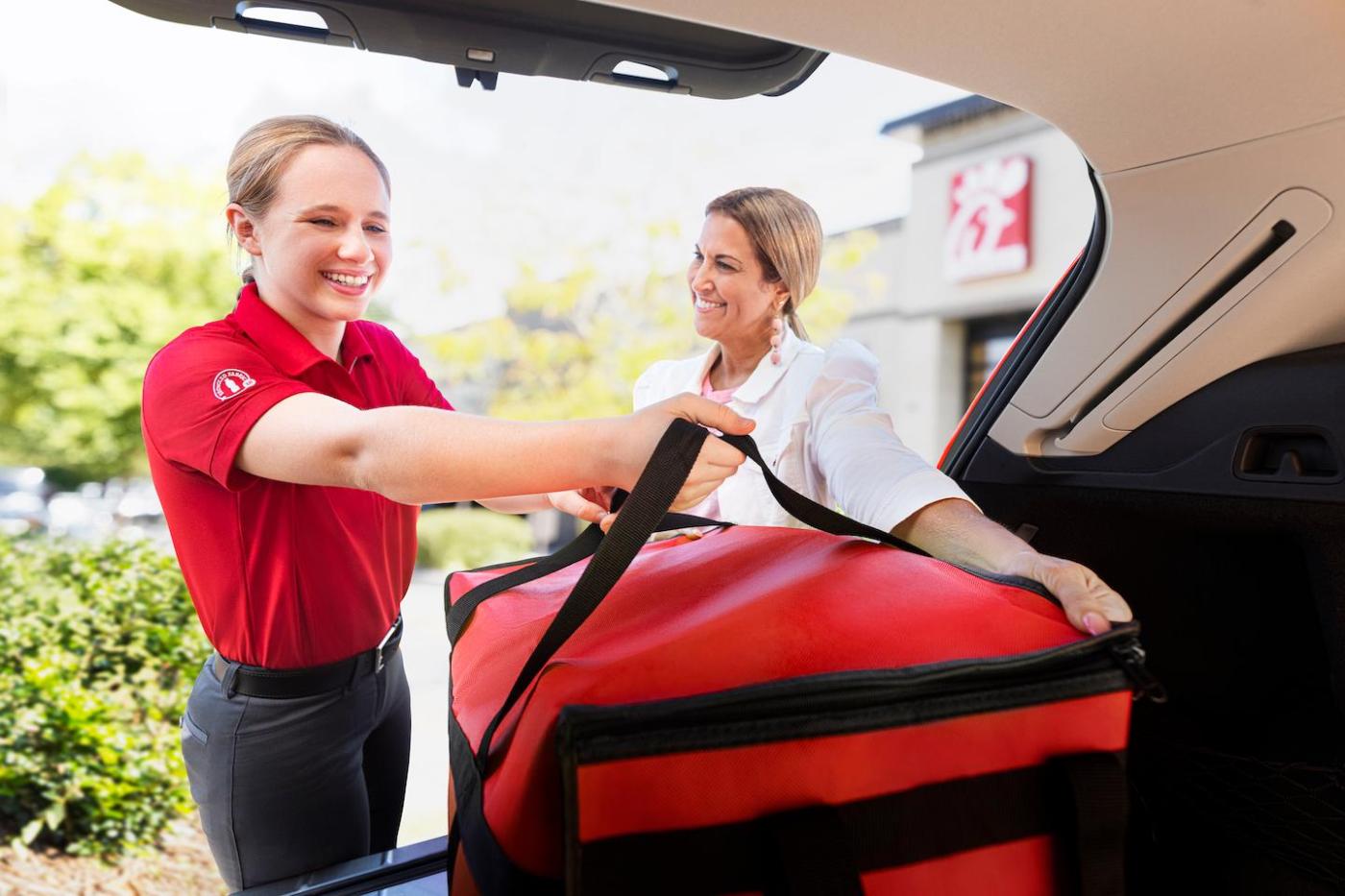 A Chick-fil-A team member loads an insulated bag into a truck.
