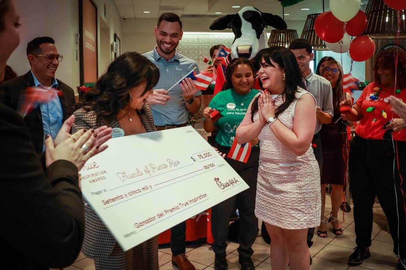 A group of people celebrate while holding a large check.