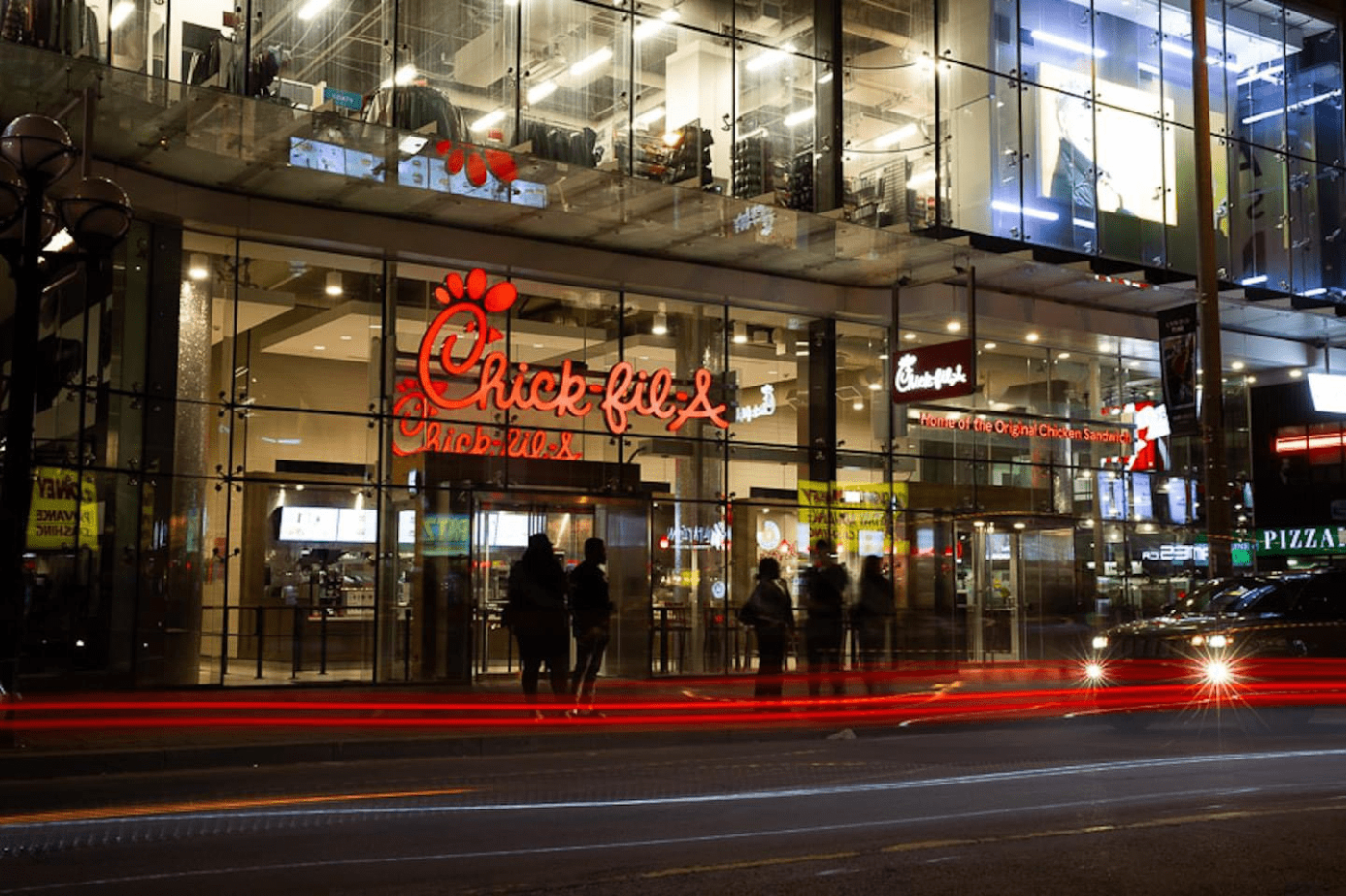 Evening street view of Chick-fil-A restaurant inside a multi-story building.
