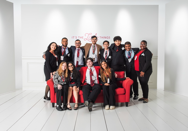 Group of Chick-fil-A Community Scholars smiling together on and around a red couch.