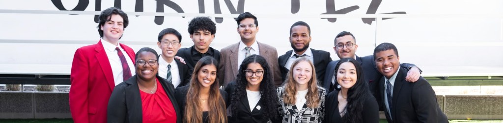 2025 Scholars in formal attire posing in front of sign