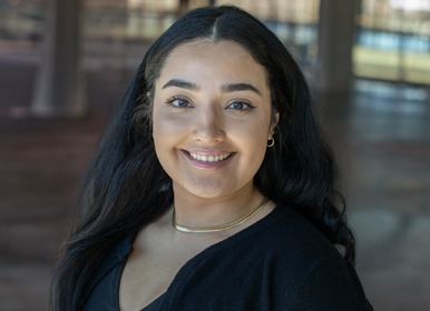 Headshot of Alejandra with a blurred indoor background.