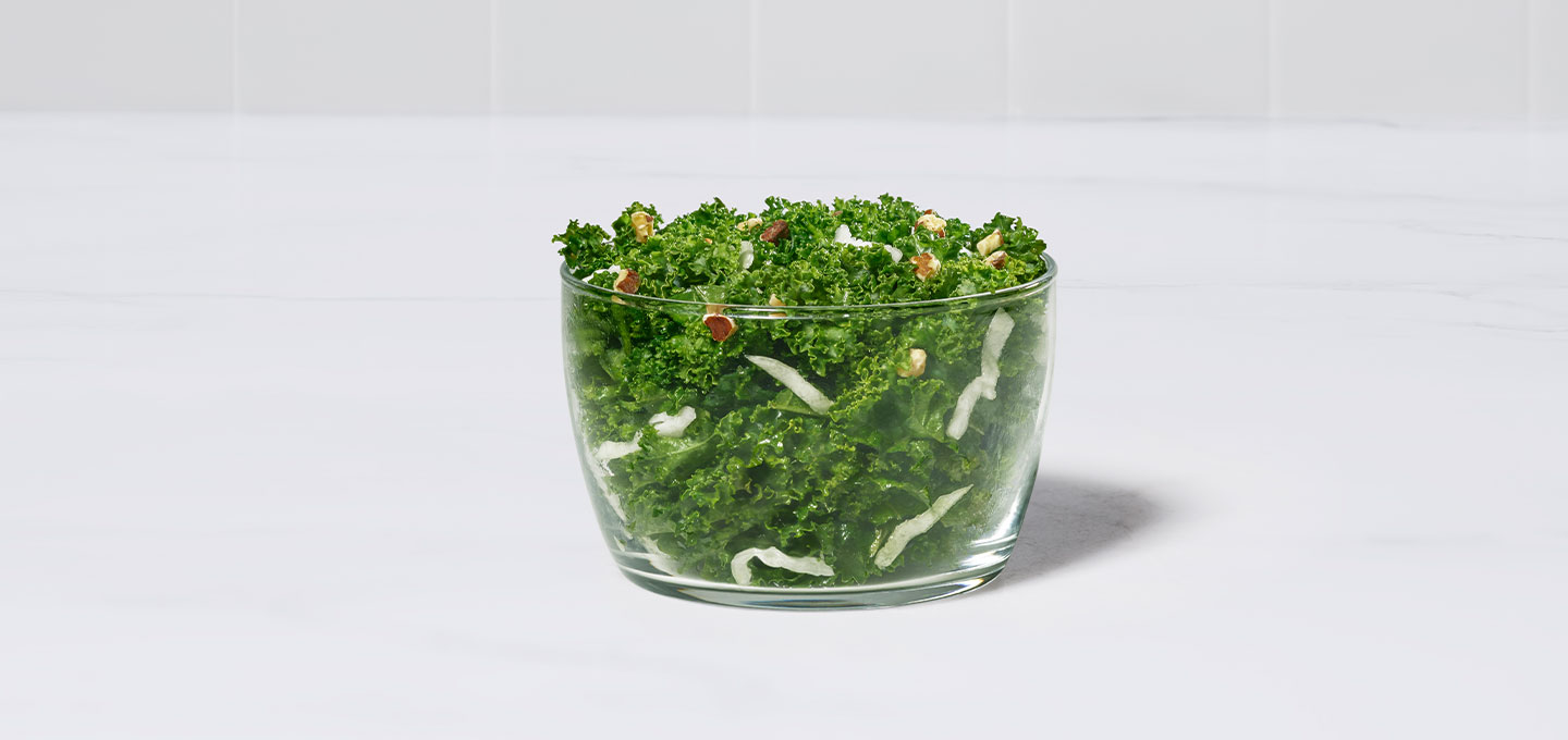 Kale Crunch Salad in a clear bowl with a gray background.