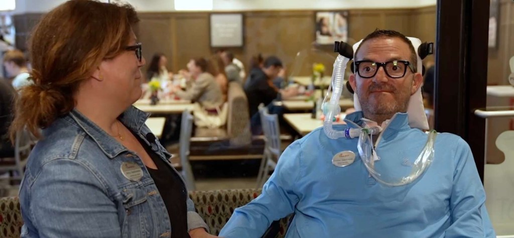 Two people sitting in a Chick-fil-A restaurant, with one person wearing a blue shirt and a medical device.